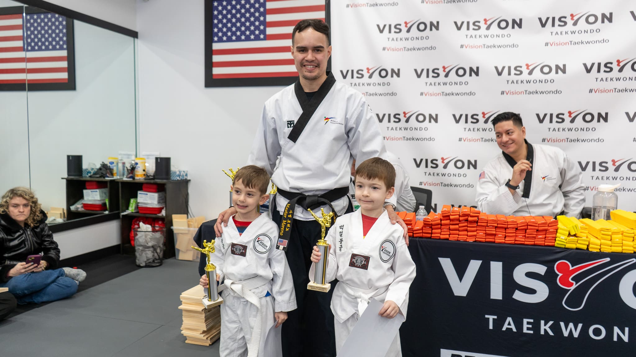 Kids in Taekwondo uniforms develop self-defense skills, self-discipline, and overall fitness while learning kick techniques, balance, and teamwork, as students train together to improve their abilities and compete in tournaments.