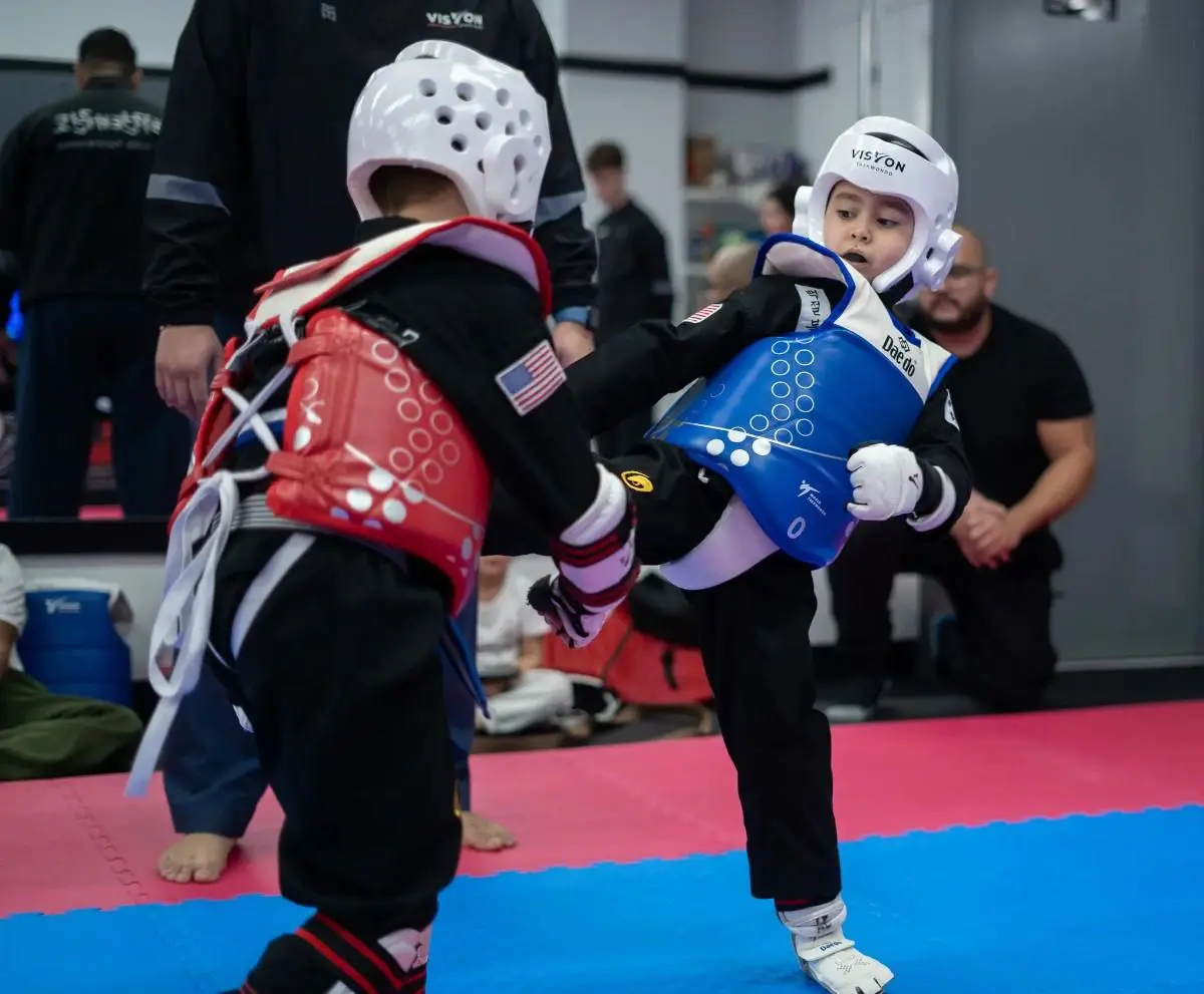 Kids sparring in taekwondo gear during youth martial arts class
