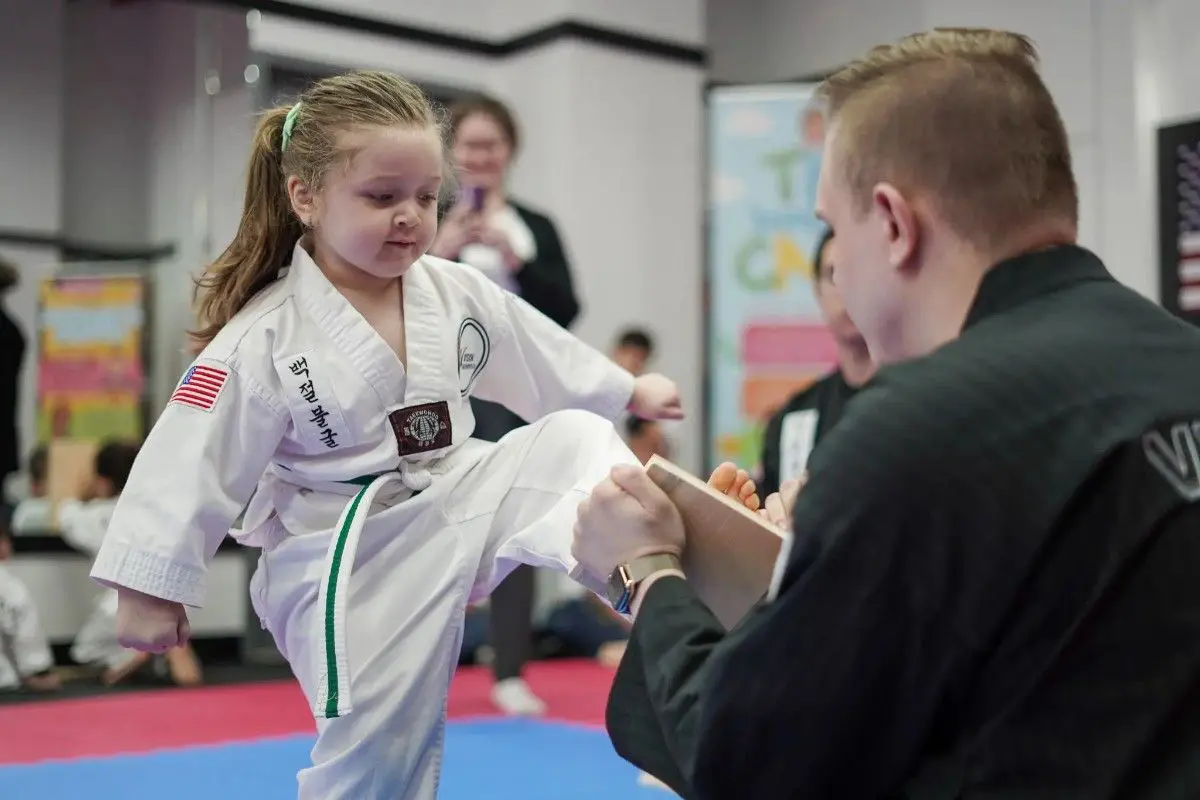 Young taekwondo student breaking board during belt testing