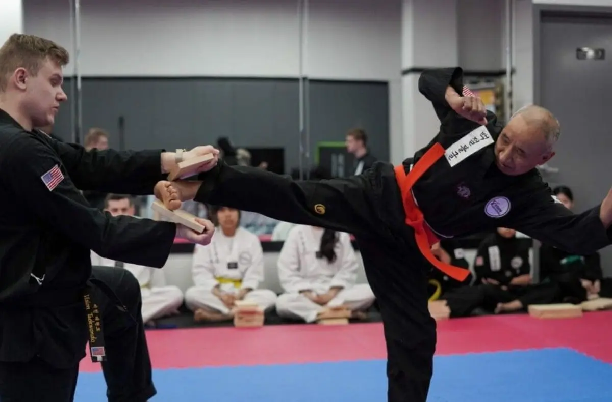 Black belt performing advanced taekwondo high kick board break