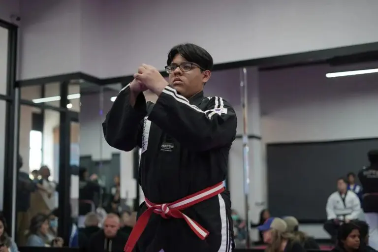 taekwondo student tying red belt before training in martial arts studio