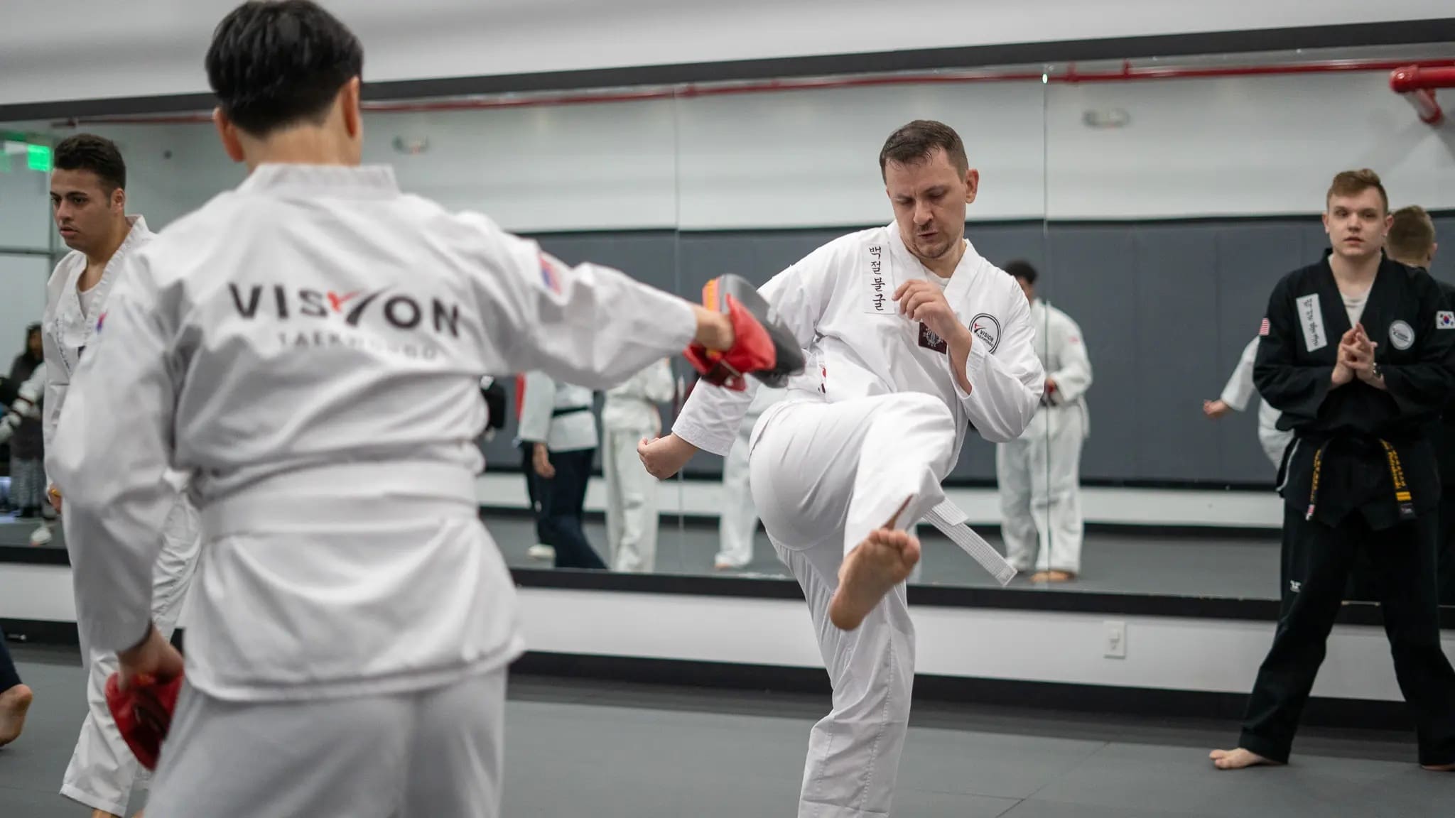 white belt in a self defense techniques for beginners class student performing kicking drills
