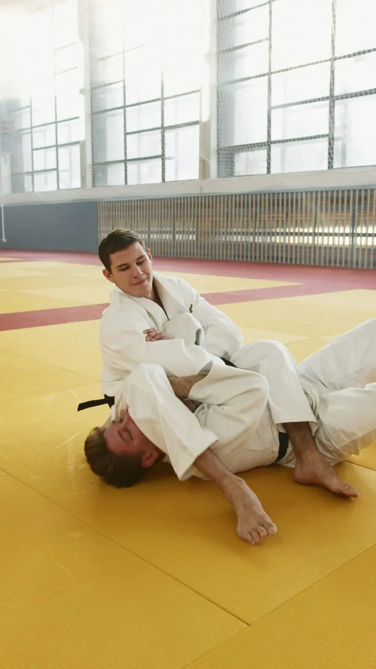 Two martial arts students practicing a ground control technique on padded mats during class, why adults learn martial arts faster