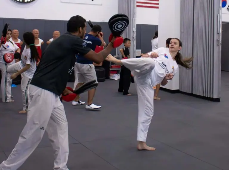 Teen martial arts students practising kicking techniques with training partners during a structured class focused on discipline, fitness, and confidence building + teen martial arts benefits