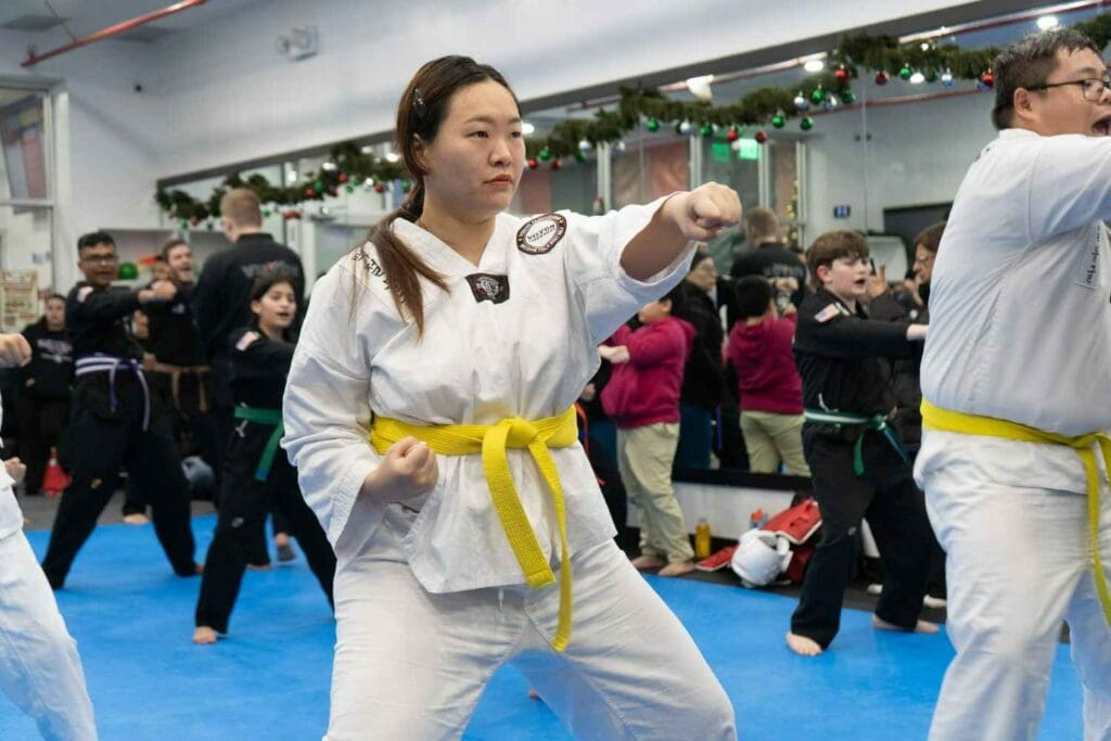 Martial arts student extending a punch during a group practice session Taekwondo kick chamber basics