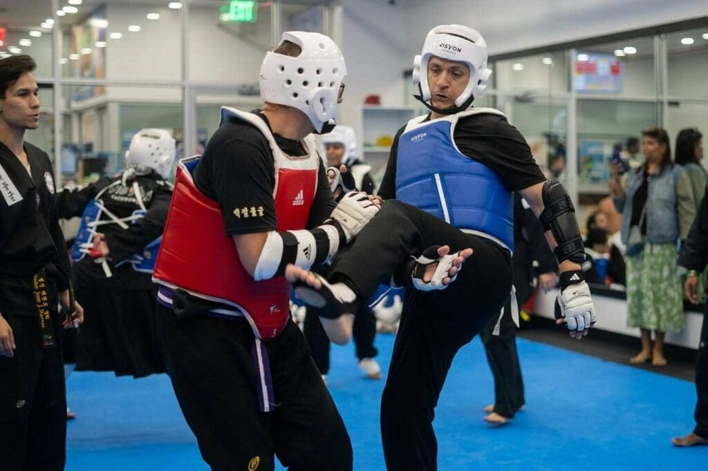 Martial arts practitioner lifting a knee to chamber a kick during a sparring drill Taekwondo kick chamber basics